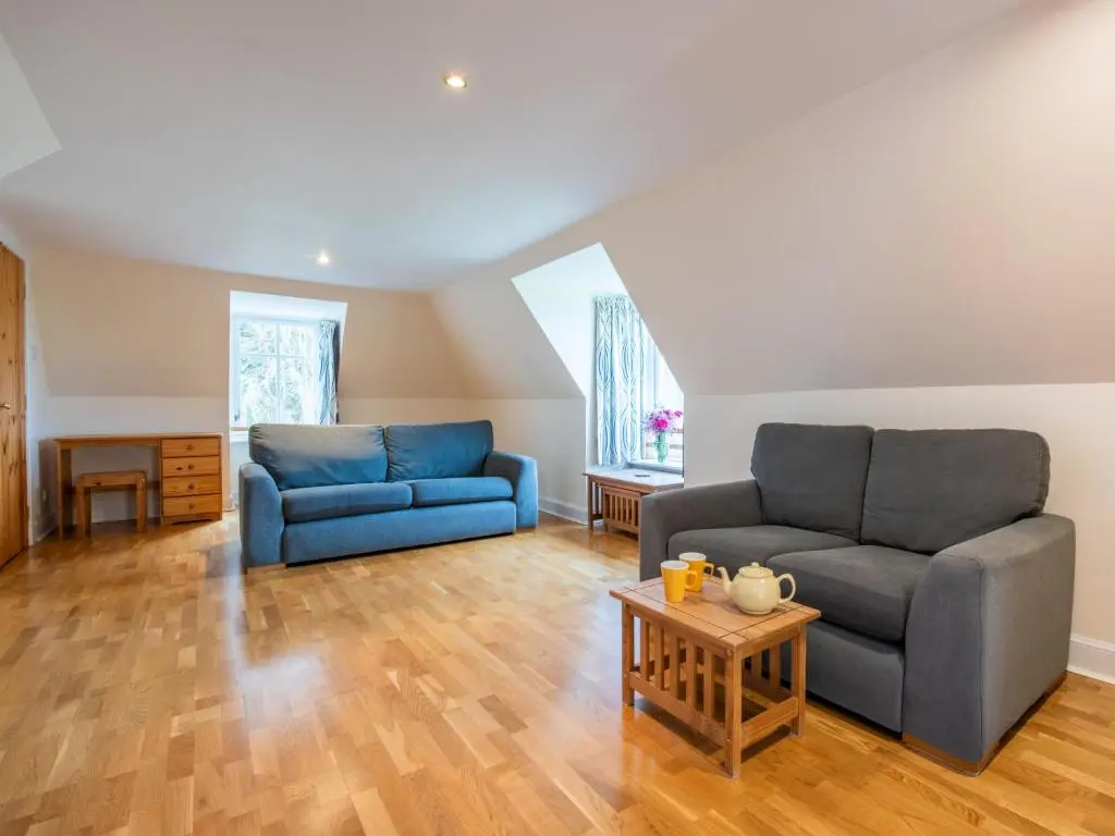 a living room with two blue couches and a table at Holiday Home Corrimony View by Interhome in Drumnadrochit