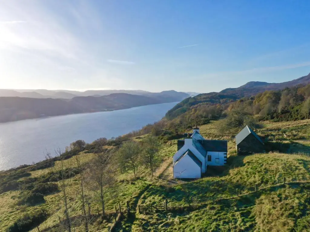 a house on a hill next to a body of water at Holiday Home Wester Bunloit by Interhome in Drumnadrochit