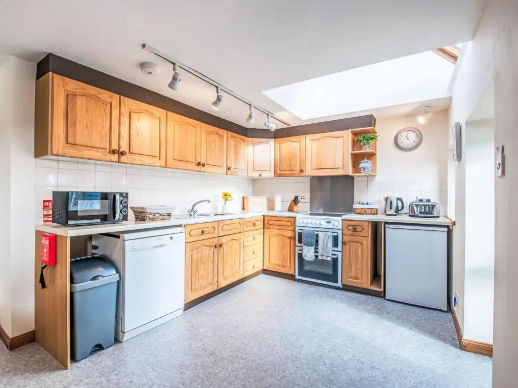 a kitchen with wooden cabinets and white appliances at Holiday Home Wester Bunloit by Interhome in Drumnadrochit