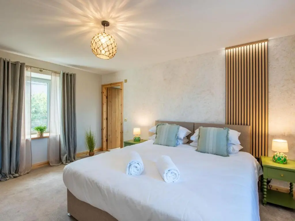 a bedroom with a large white bed with blue pillows at Holiday Home Cooriedoon by Interhome in Hopeman