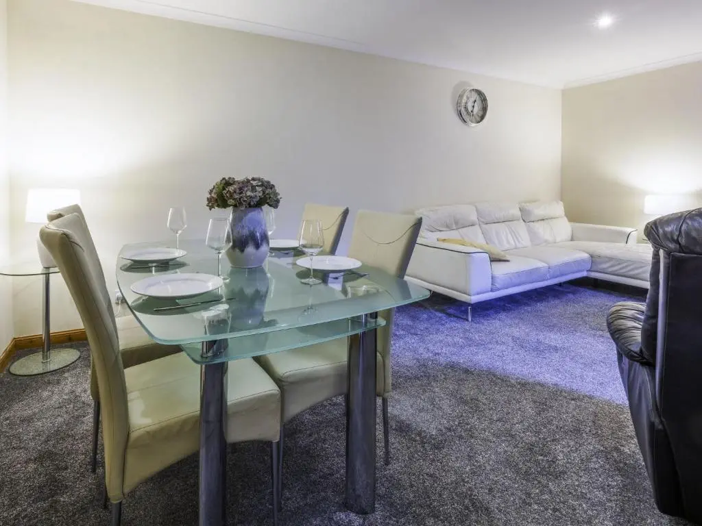 a living room with a glass table and a couch at Apartment Pitgaveny Apartment by Interhome in Lossiemouth