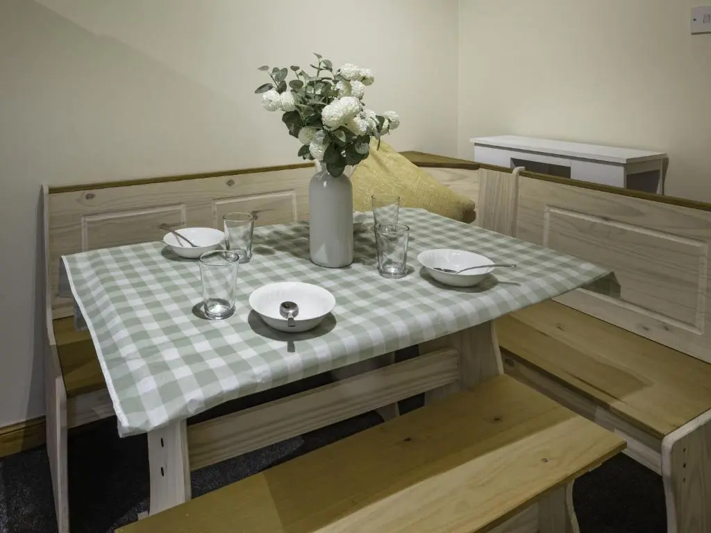 a table with a vase of flowers on top of it at Apartment Pitgaveny Apartment by Interhome in Lossiemouth