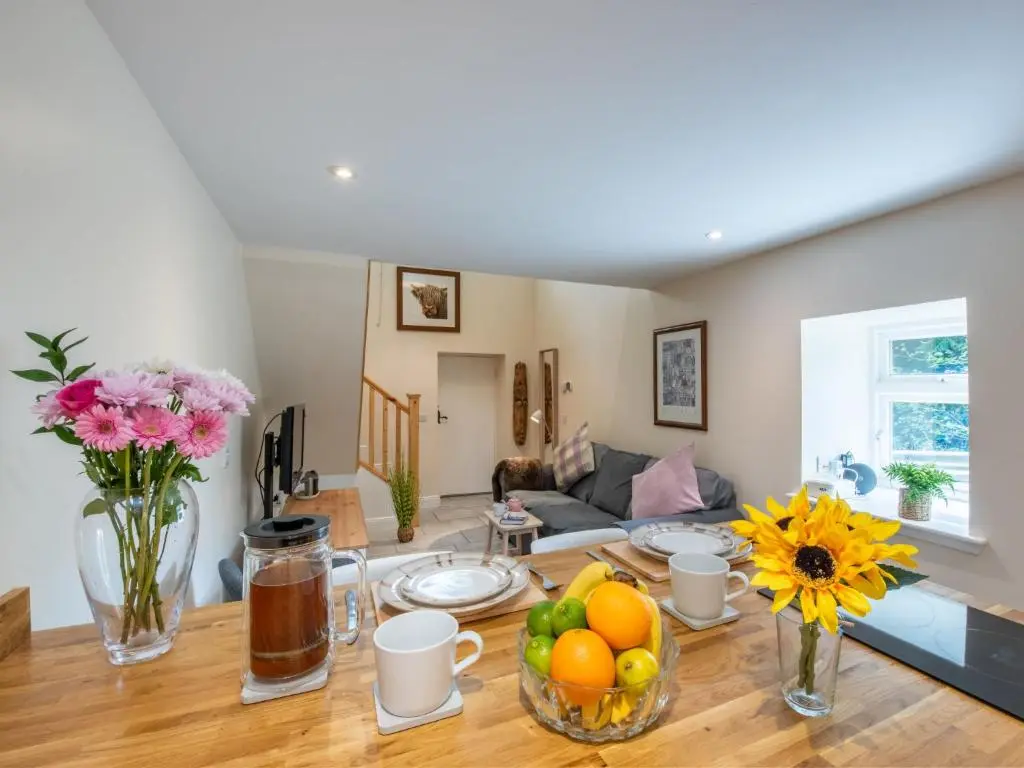 a living room with a table with fruits and flowers at Holiday Home Wayside Bothy by Interhome in Drumnadrochit