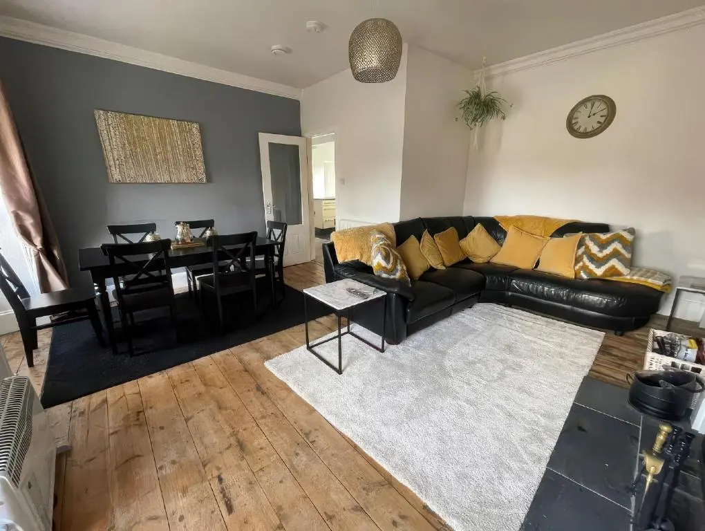 a living room with a black leather couch and a table at Home in Forres, Moray in Forres