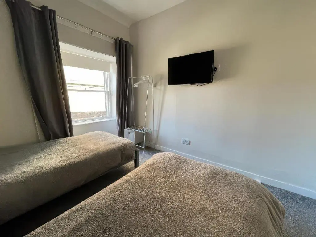 a bedroom with two beds and a tv on the wall at Home in Forres, Moray in Forres