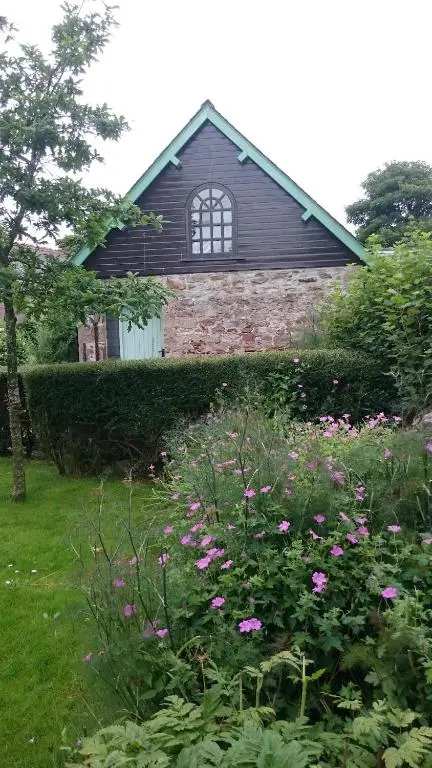 a house with a garden with flowers in front of it at Special Offer, Cosy Cottage Near the Sea in Embo in Embo