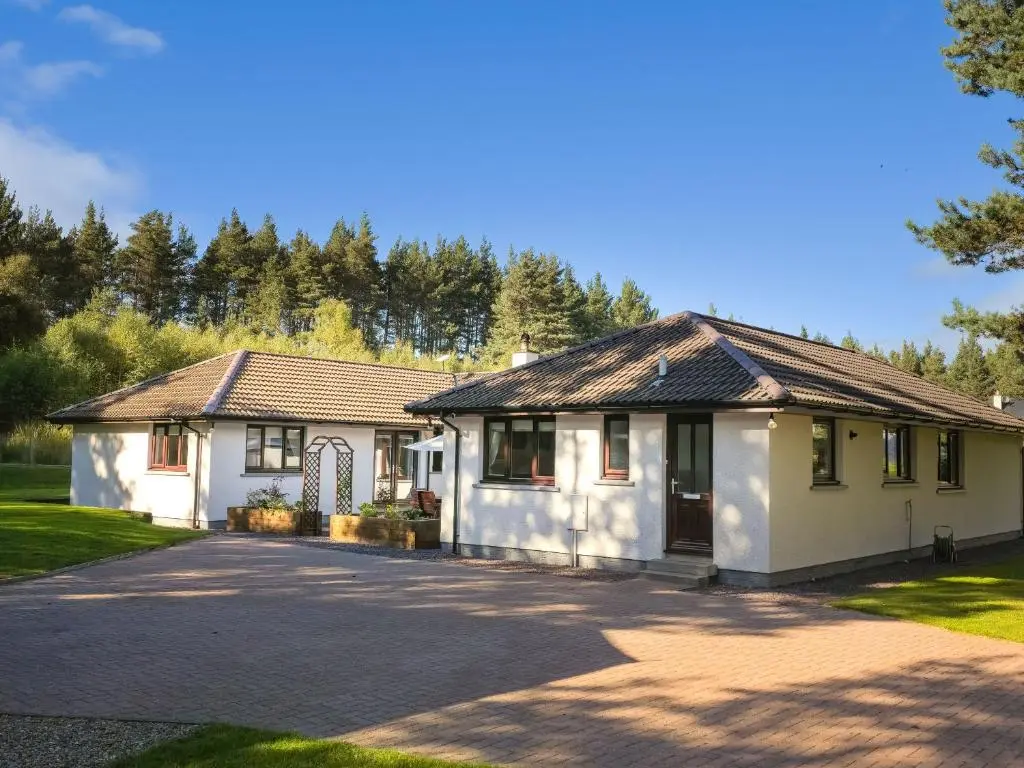 a white house with a driveway at Woodland House in Tomatin