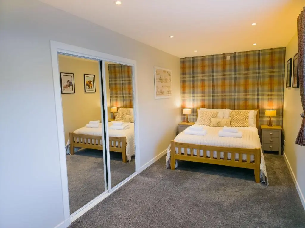 a bedroom with two beds and a mirror at Woodland House in Tomatin