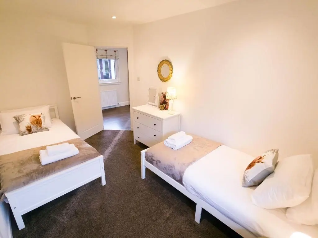 a bedroom with two beds and a mirror at Woodland House in Tomatin