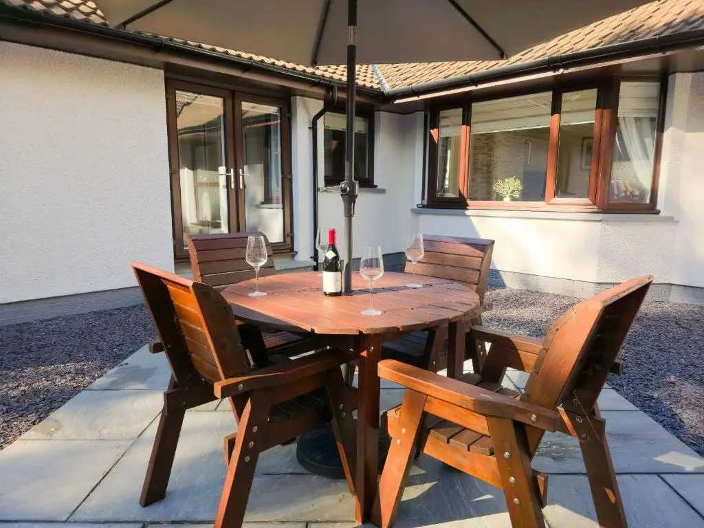 a wooden table with wine glasses on a patio at Woodland House in Tomatin