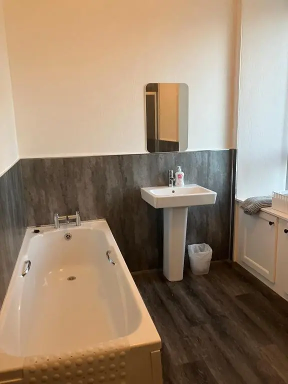 a bathroom with a bath tub and a sink at Toll House in Wick