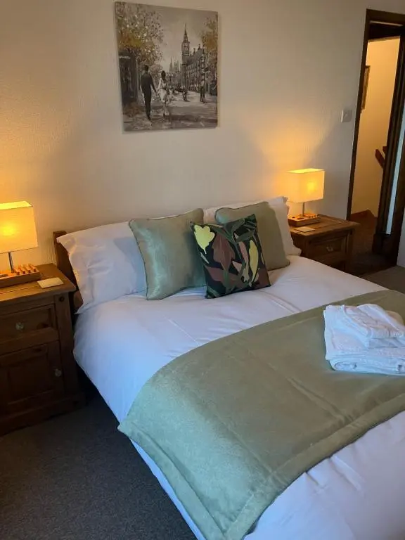 a bedroom with a white bed with two lamps at Toll House in Wick