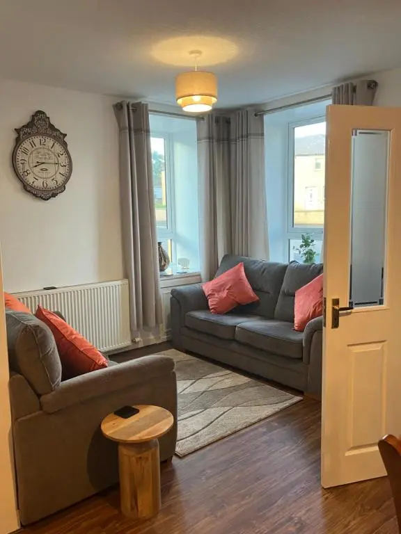 a living room with a couch and a clock on the wall at Toll House in Wick