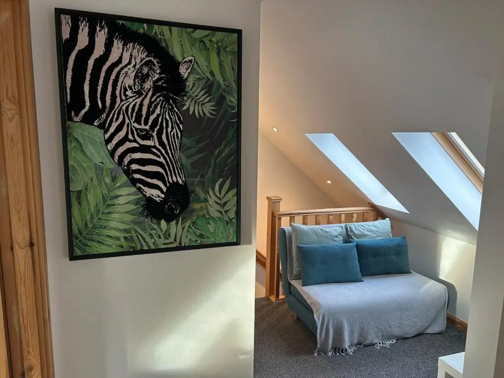a painting of a zebra on a wall next to a chair at Helen's Hoose in Aviemore