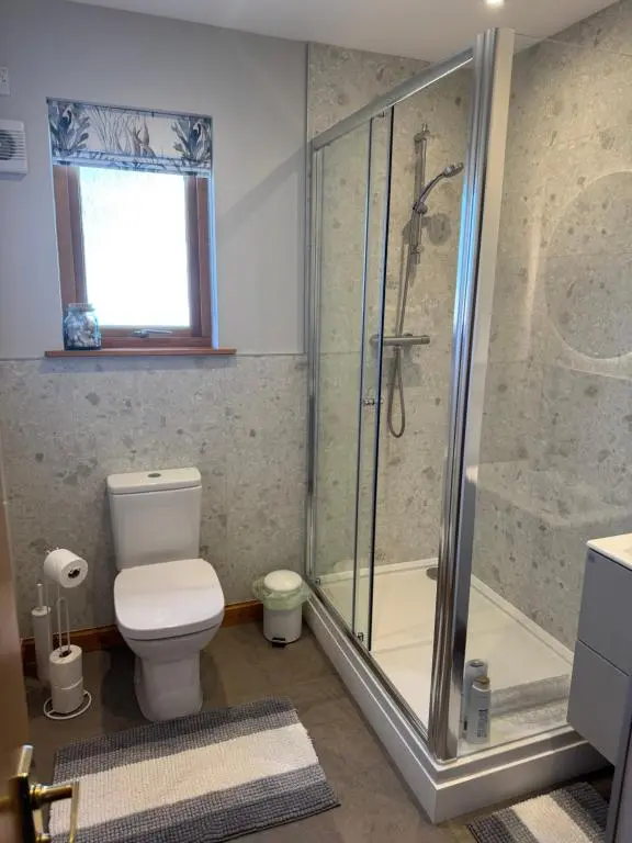 a bathroom with a toilet and a glass shower at Firth Tides in Nairn