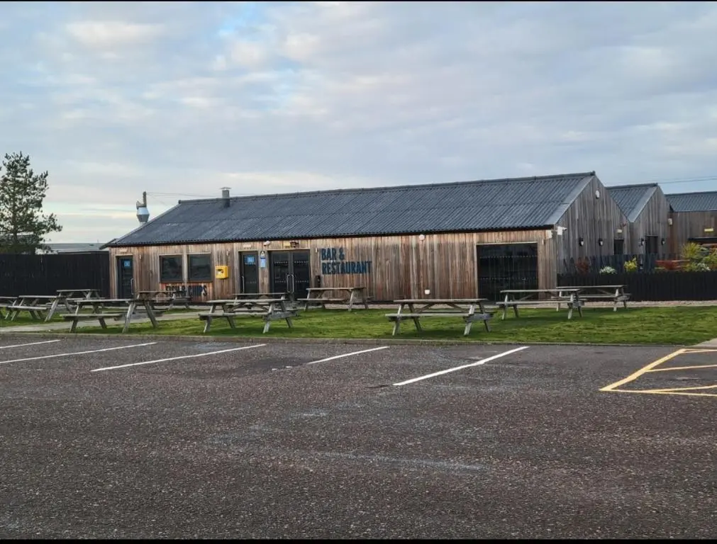 a group of benches in a parking lot in front of a building at Silversands - Private Caravan Let in Lossiemouth