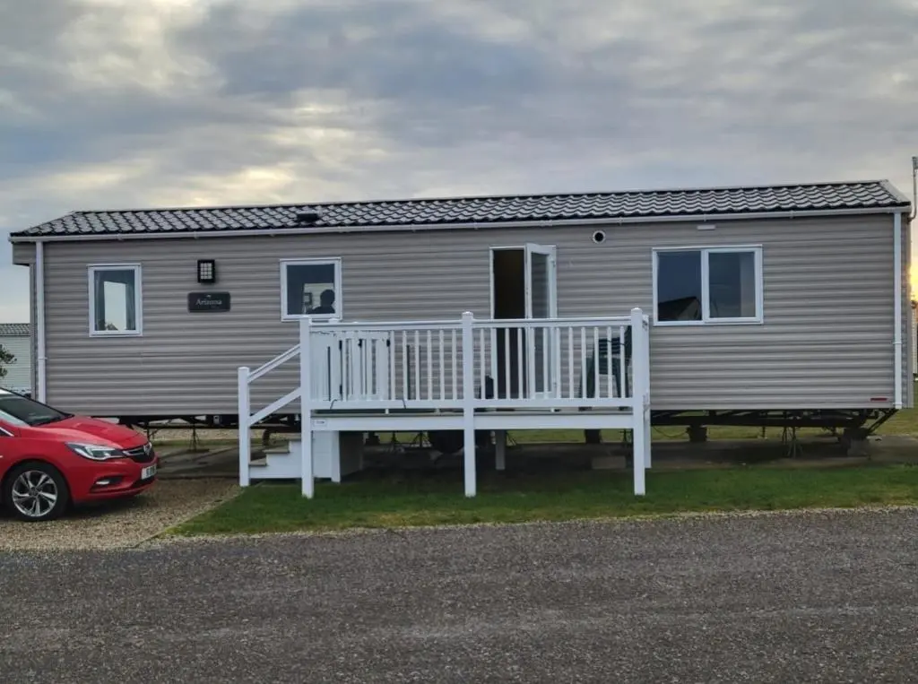 a house with a porch and a car parked in front of it at Silversands - Private Caravan Let in Lossiemouth