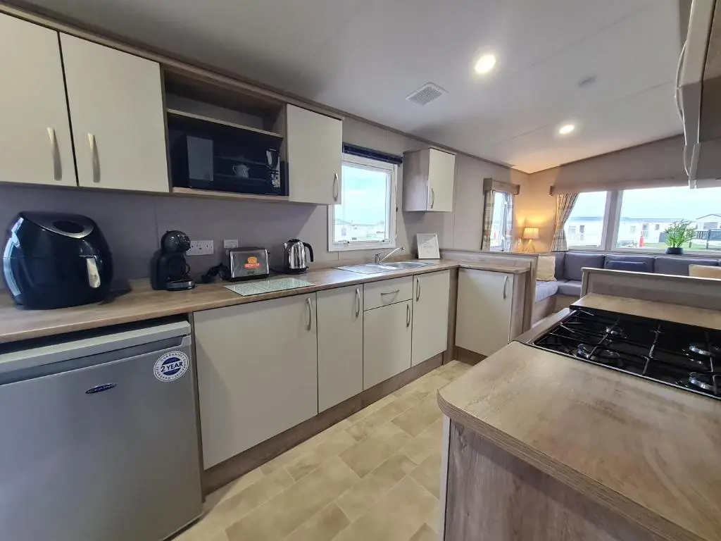 a kitchen with white cabinets and a counter top at Silversands - Private Caravan Let in Lossiemouth