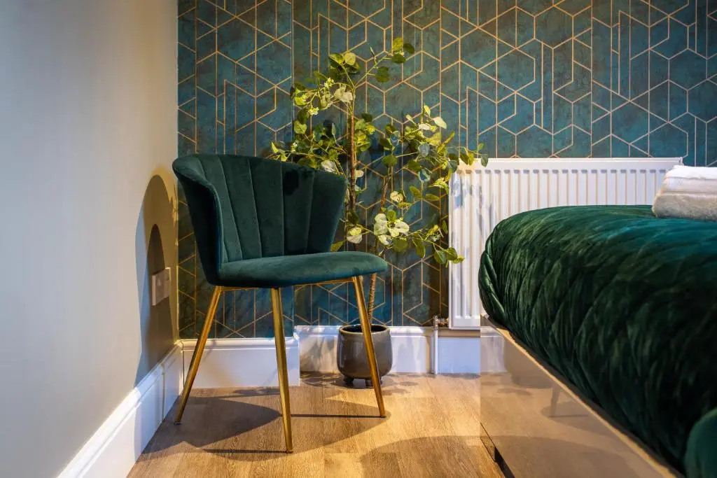 a green chair in a bedroom with a plant at 17 at the Bell Tower in Inverness