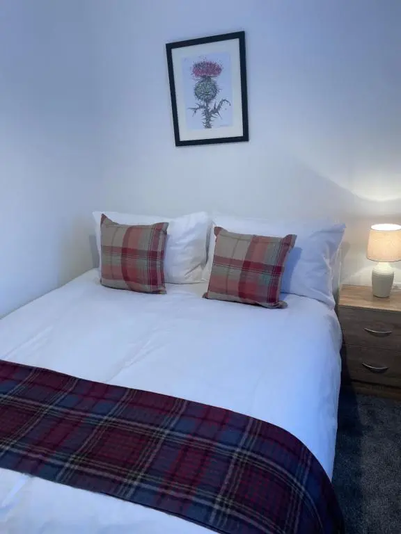a bedroom with a white bed with two pillows at Garden Room at Tartan House in Inverness