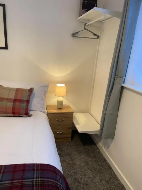 a bedroom with a bed and a lamp on a night stand at Garden Room at Tartan House in Inverness