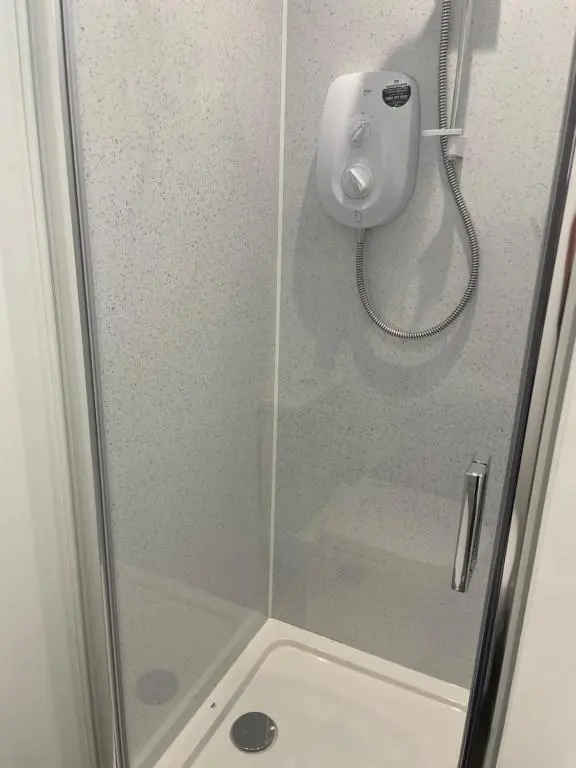 a shower with a glass door in a bathroom at Garden Room at Tartan House in Inverness
