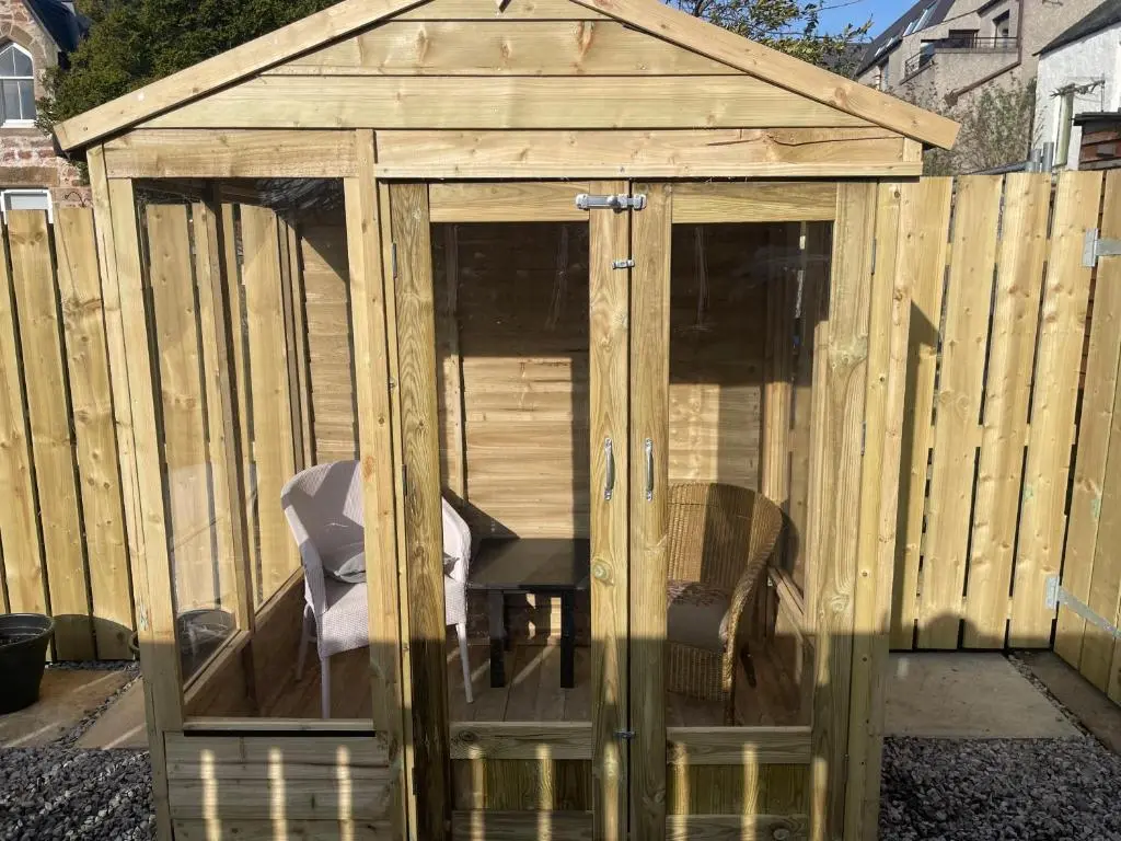 a wooden greenhouse with a chair in it at Garden Room at Tartan House in Inverness