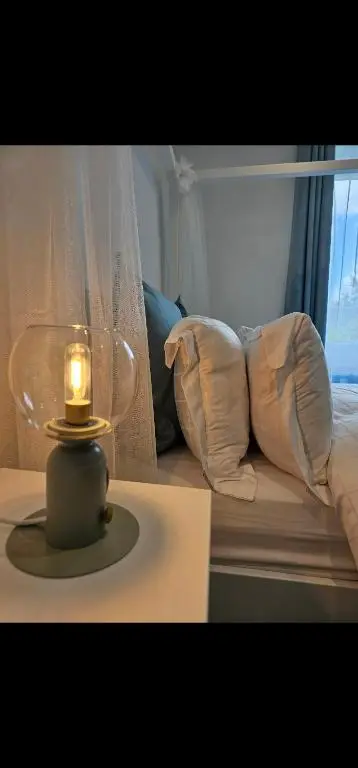 a lamp on a table next to a bed with pillows at Inverness City Centre Modern Apartment in Dalneigh