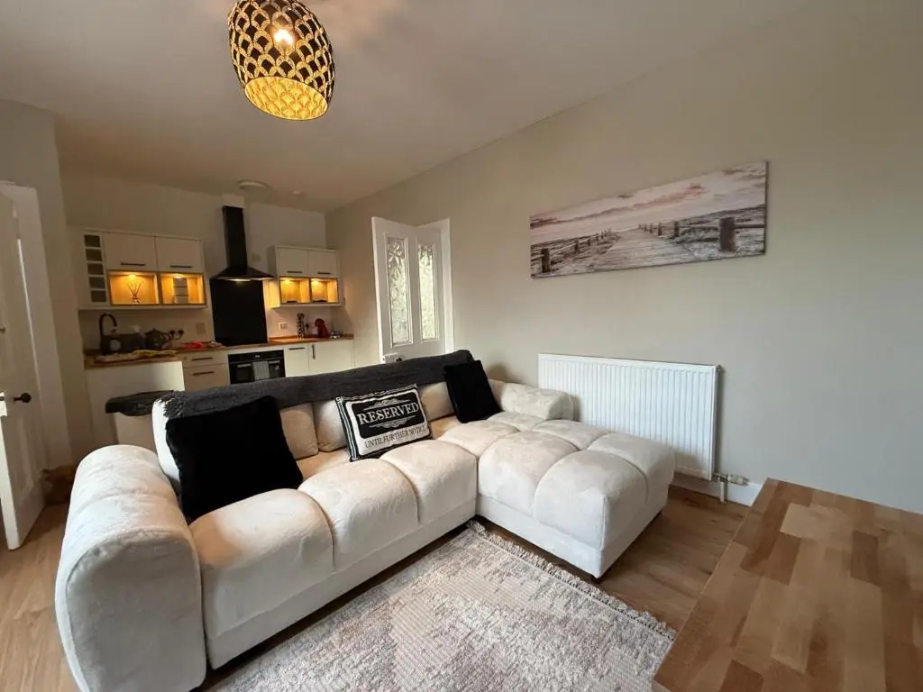 a living room with a white couch and a kitchen at The Nairn Neuk - Couples Cosy Getaway in Nairn