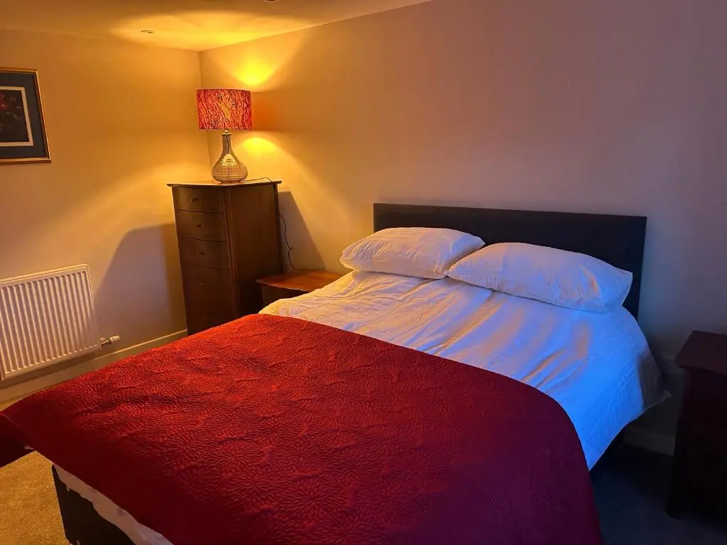 a bedroom with a bed with a red blanket at Calsie Cottage, Clatt in Kirktown of Clatt