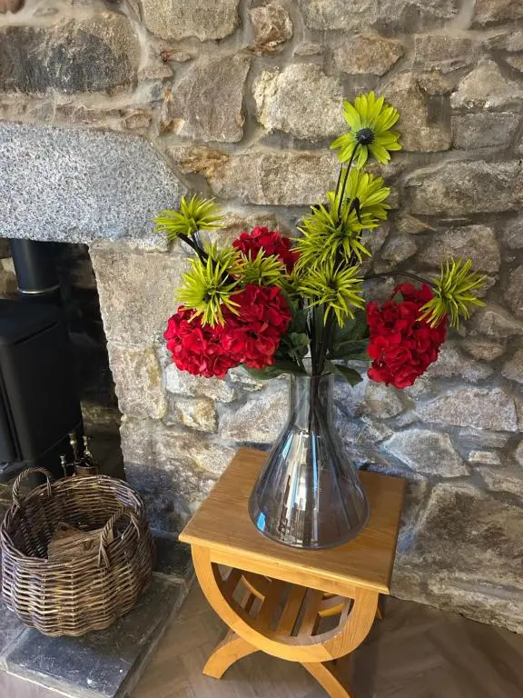 a vase with red and yellow flowers on a table at Calsie Cottage, Clatt in Kirktown of Clatt