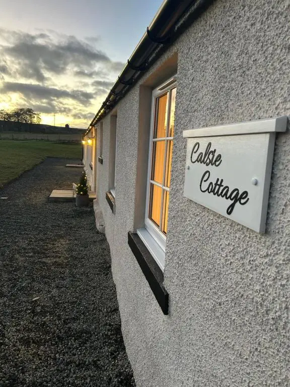 a sign on the side of a building with a window at Calsie Cottage, Clatt in Kirktown of Clatt