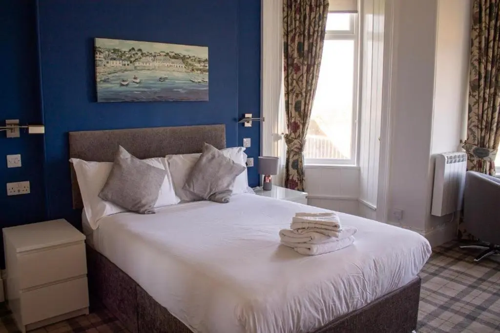 a blue bedroom with a bed with towels on it at Poseidon's in Lossiemouth