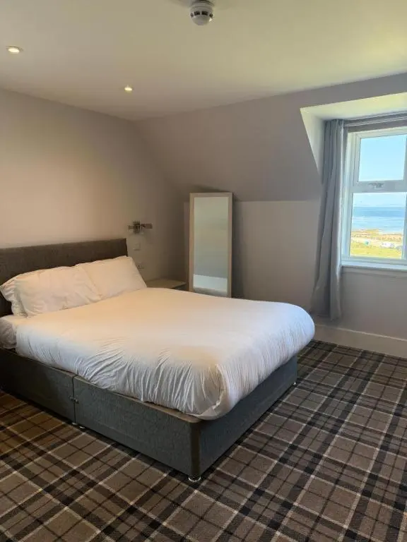a bedroom with a large bed with a window at Poseidon's in Lossiemouth