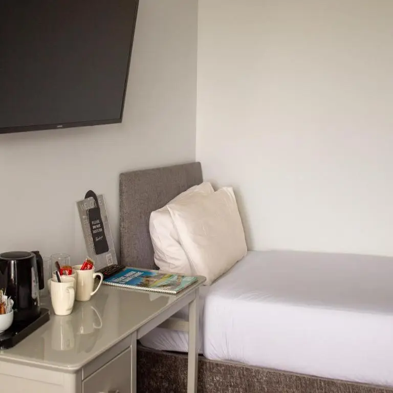 a small room with a bed and a desk with a table at Poseidon's in Lossiemouth
