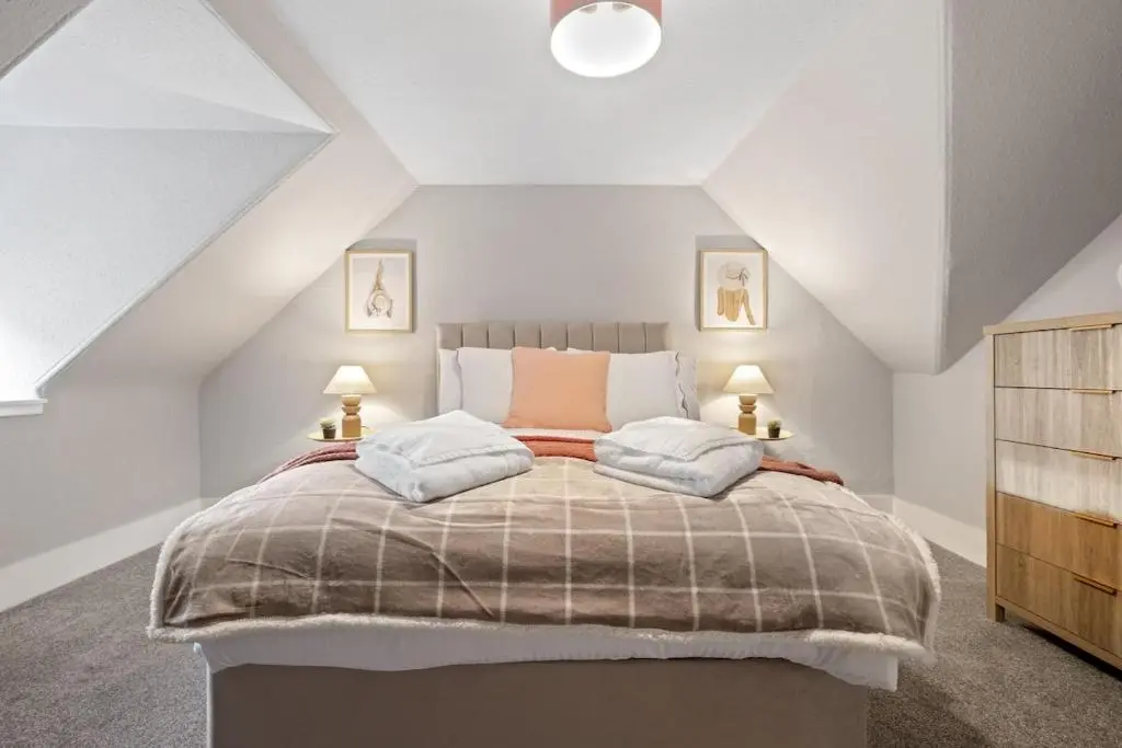 a bedroom with a large bed in a attic at Leo Apartment - 4 Bedroom Flat in Nairn in Nairn