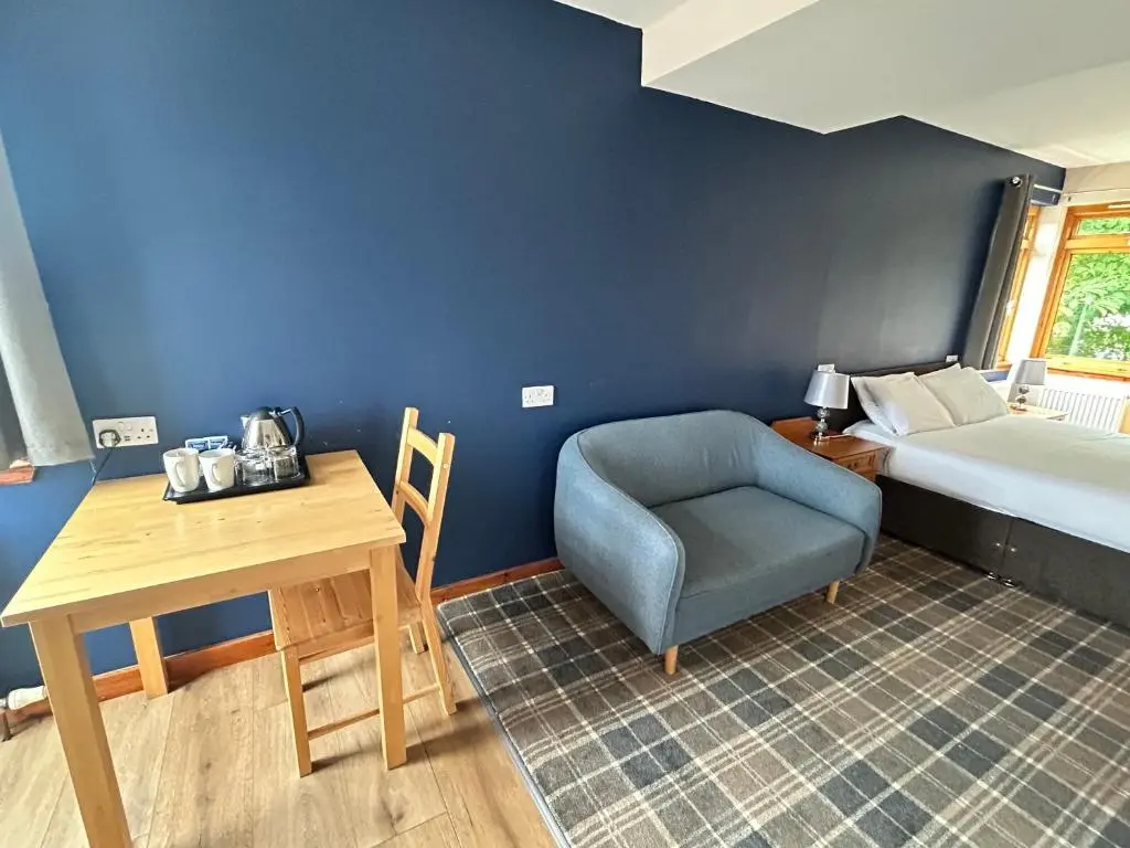 a room with a bed and a chair and a table at Westend Hotel & Bar in Nairn