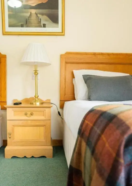 a bedroom with a bed and a lamp on a night stand at Westend Hotel & Bar in Nairn
