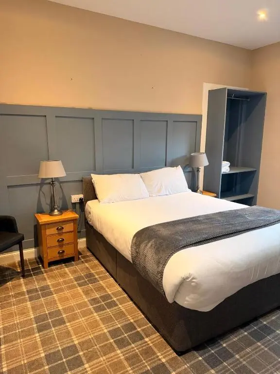 a bedroom with a bed and a chair and a table at Westend Hotel & Bar in Nairn