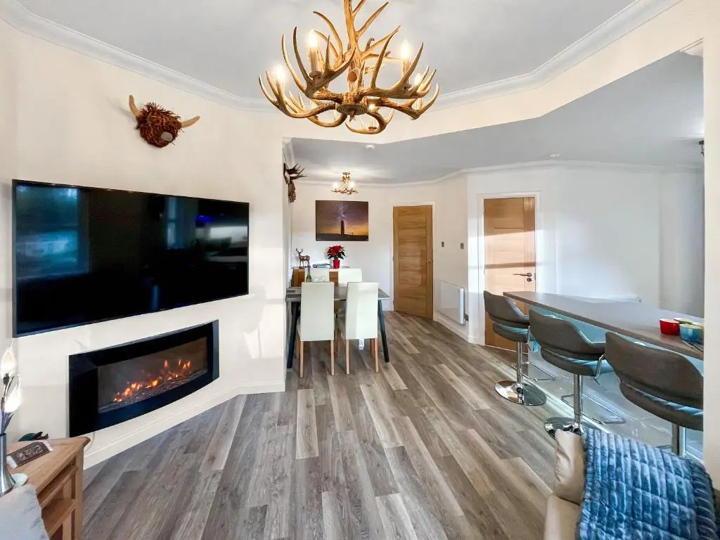 a living room with a fireplace and a dining room at Dee View Apartment in Banchory