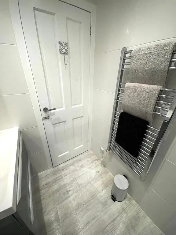 a bathroom with a white door and a wooden floor at Culduthel Court Apartment in Inshes