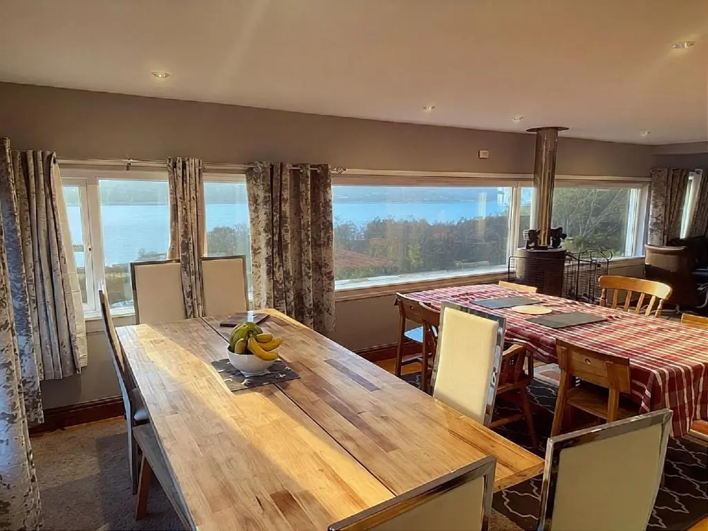a dining room with a table and a large window at Overscaig House in Lairg