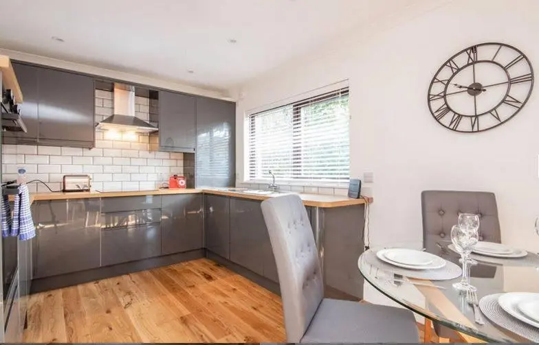 a kitchen with a table and a clock on the wall at 2 Bedroom Macewen Drive in Inverness