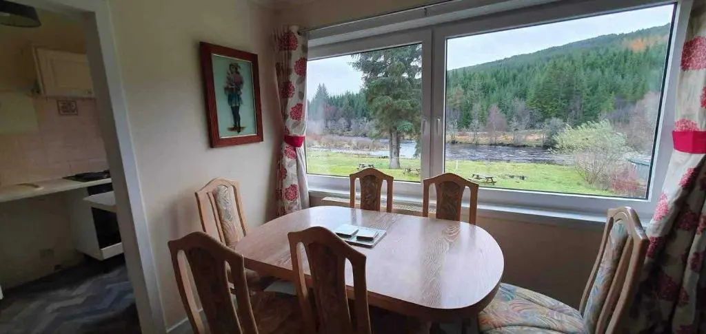 a table and chairs in a room with a large window at River View in Garve