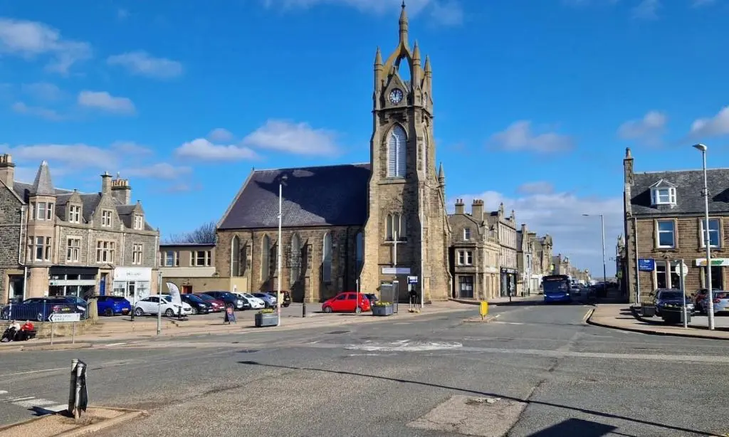 an old church with a clock tower on a street at Rook View, Modern Coastal Retreat with Free Parking in Buckie