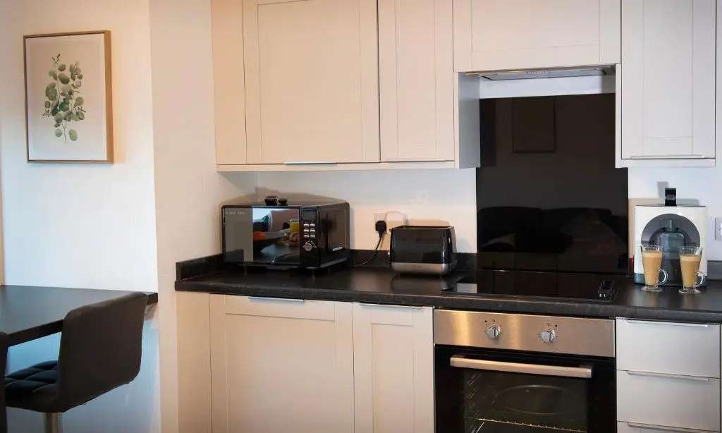 a kitchen with white cabinets and a stove top oven at Rook View, Modern Coastal Retreat with Free Parking in Buckie