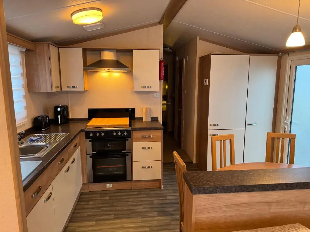 a kitchen with white cabinets and a counter top at Casa MALC Caravan in Lossiemouth