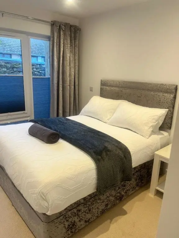a bed in a bedroom with a large window at Newly Renovated Luxuary Flat overlooking Wick Bay in Wick