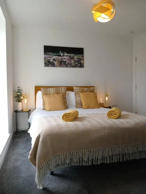 a bedroom with a large bed with yellow pillows at Modern 4 Bed Highland Home in Culloden