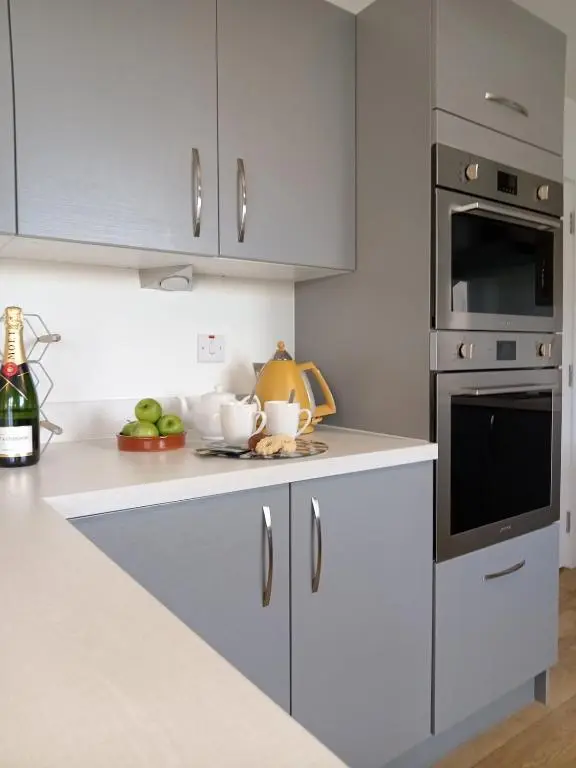 a kitchen with white cabinets and silver appliances at Modern 4 Bed Highland Home in Culloden